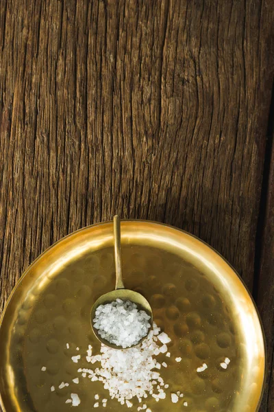 Salt in spoon and plate on wooden table — Stock Photo, Image