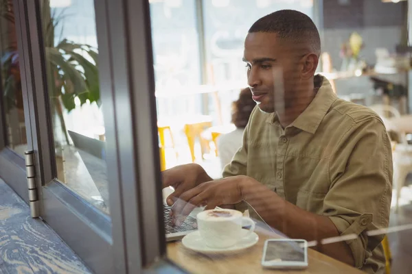 Man using laptop seen through glass window — Stock Photo, Image