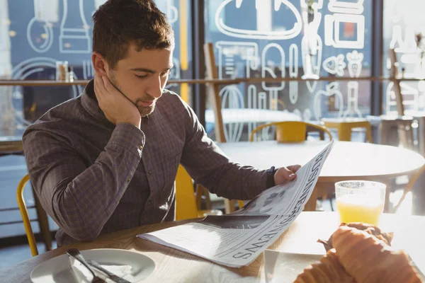 Businessman reading newspaper in cafe — Stock Photo, Image