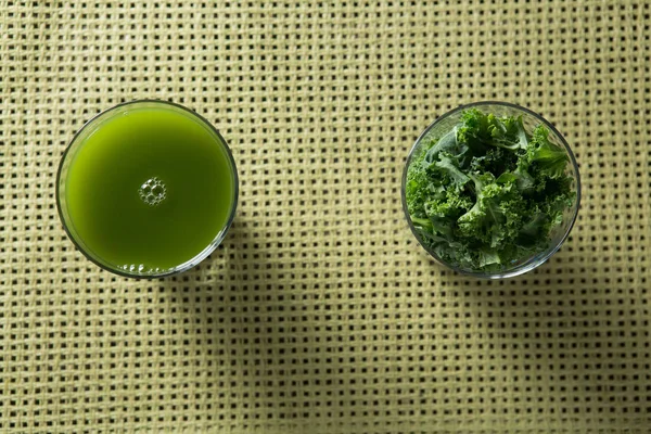 Suco de couve fresco e folhas em vidro na mesa — Fotografia de Stock