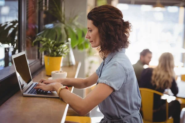 Mujer usando el ordenador portátil en el mostrador en la cafetería —  Fotos de Stock