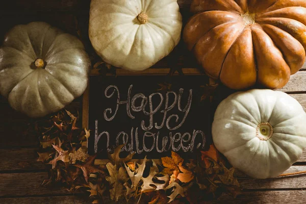 Щасливий текст Хеллоуїна на шиферу гарбузами серед осіннього листя — стокове фото