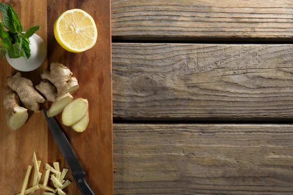 Lemon and ginger on cutting board over table — Stock Photo, Image