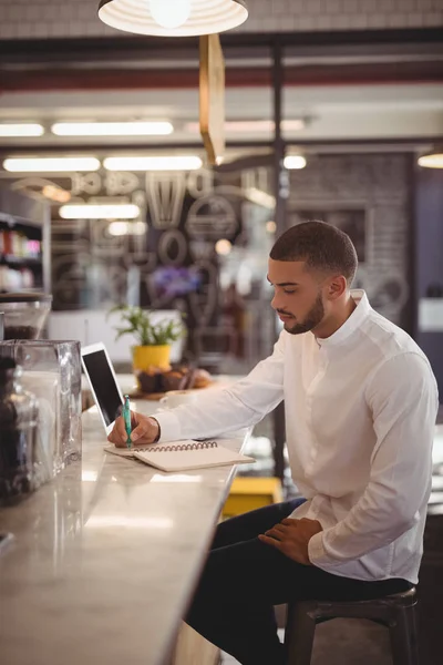 Propriétaire masculin écrivant sur le bloc-notes au comptoir — Photo