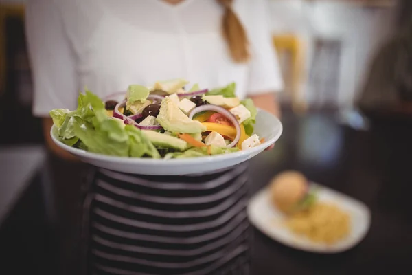 Servitris hålla fräsch grekisk sallad i plattan — Stockfoto