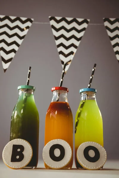 Biscoitos com texto boo por bebidas coloridas em garrafas — Fotografia de Stock