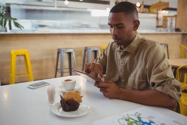Młody człowiek za pomocą cyfrowego tabletu w kawiarni — Zdjęcie stockowe
