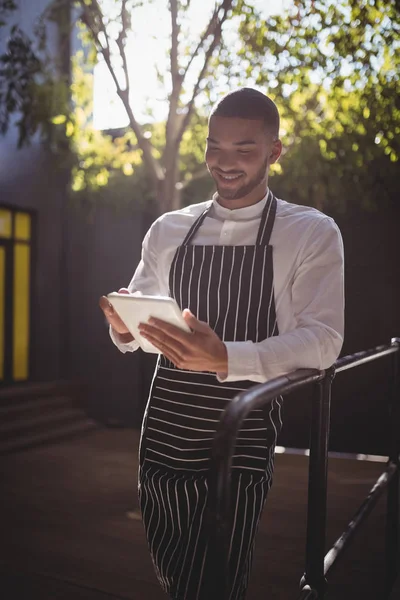 Kelner przy użyciu tablet podczas gdy pochylony na poręczy — Zdjęcie stockowe