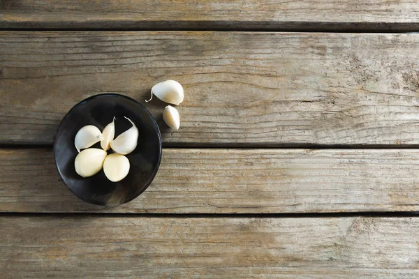 Garlics in plate on wooden table — Stock Photo, Image