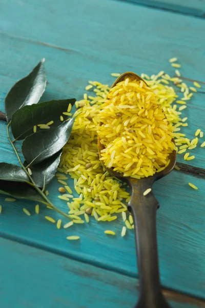 Arroz amarillo orgánico crudo y hojas de curry — Foto de Stock