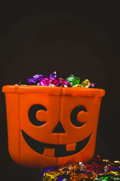 Balde com chocolates coloridos durante o Halloween — Fotografia de Stock