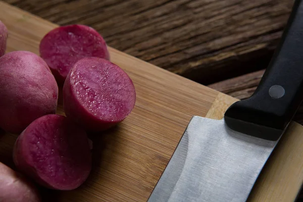 Sweet potatoes and knife on a chopping board — Stock Photo, Image