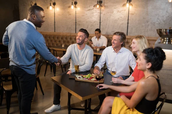 Freunde beim Händeschütteln beim Essen — Stockfoto