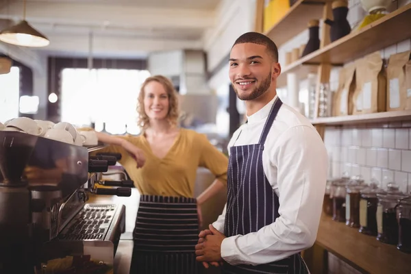 Camarero y camarera de pie junto a la cafetera espresso — Foto de Stock