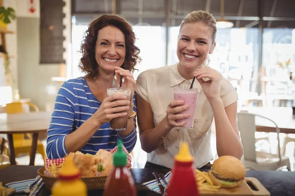 Amigos do sexo feminino beber milkshake no café — Fotografia de Stock