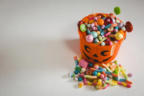 Balde com vários alimentos doces no fundo branco durante o Halloween — Fotografia de Stock