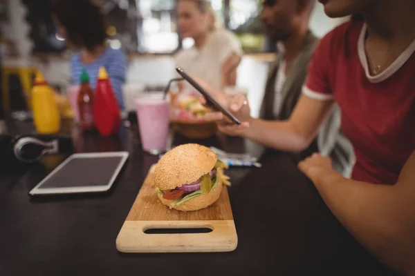 Vrouw met behulp van smartphone met Hamburger — Stockfoto