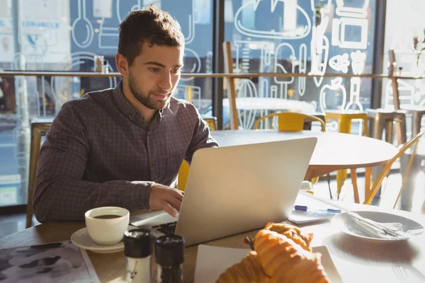 Affärsman med frukost med laptop — Stockfoto