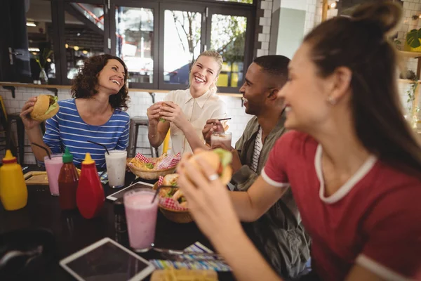 Amigos sentados com comida e bebida à mesa — Fotografia de Stock