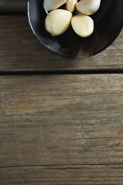 Ajos en plato sobre mesa de madera —  Fotos de Stock