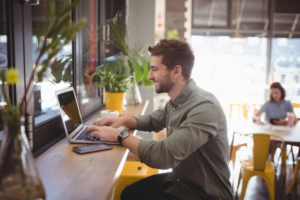 Uomo digitando sul computer portatile alla caffetteria — Foto Stock