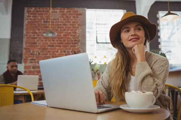 Thoughtful woman with laptop looking away — Stock Photo, Image