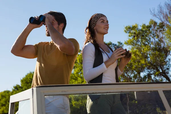 Couple using binoculars in off road vehicle — Stock Photo, Image