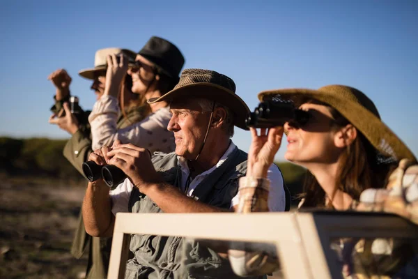 Amici che guardano attraverso il binocolo durante il safari — Foto Stock