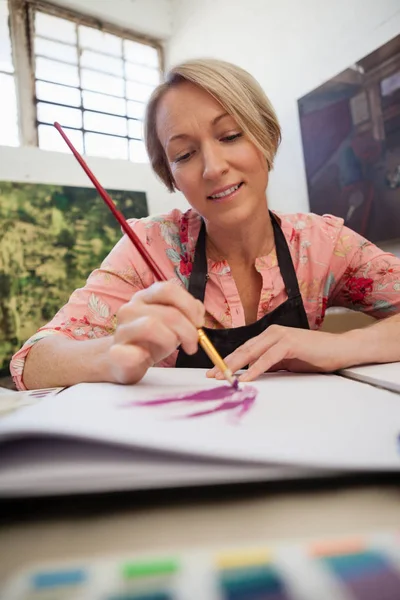 Vrouw schilderij bij de opstelling van boek — Stockfoto