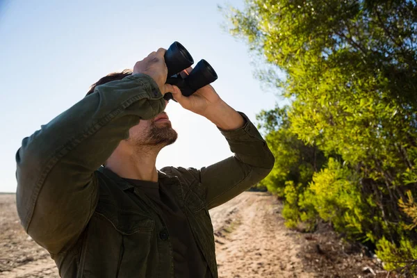 Hombre mirando a través de binocular en el campo —  Fotos de Stock