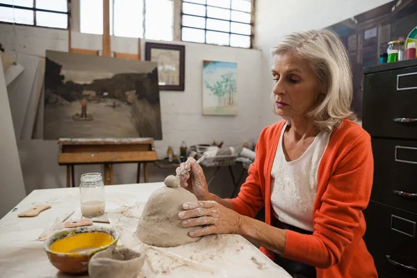 Mujer mayor dando forma a una arcilla — Foto de Stock