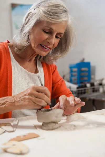 Mujer mayor atenta dando forma a una olla de barro — Foto de Stock