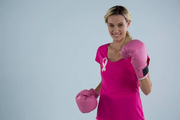 Vrouw met bokshandschoenen en en roze lint — Stockfoto