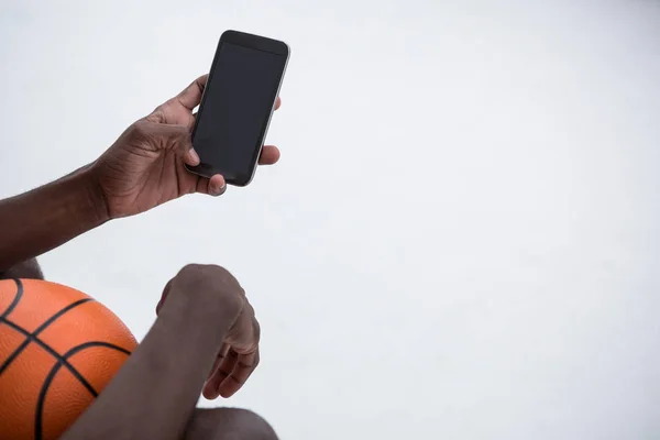 Player holding basketball while using phone — Stock Photo, Image