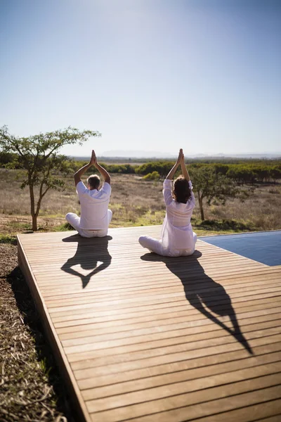 Couple pratiquant le yoga sur planche de bois — Photo