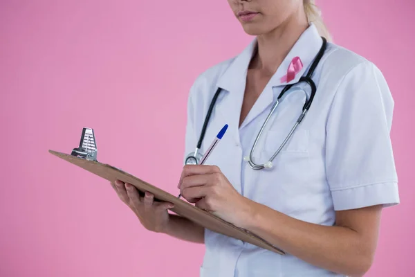 Vrouwelijke arts schrijven op Klembord — Stockfoto