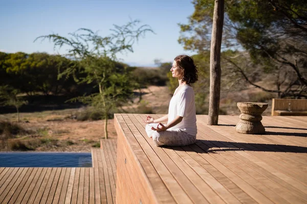Frau praktiziert Yoga auf Holzplanke — Stockfoto