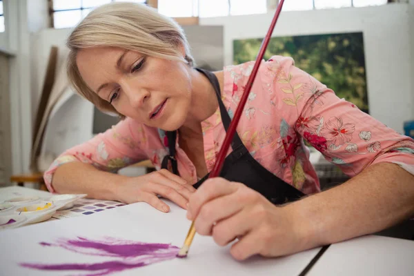 Vrouw schilderij bij de opstelling van boek — Stockfoto