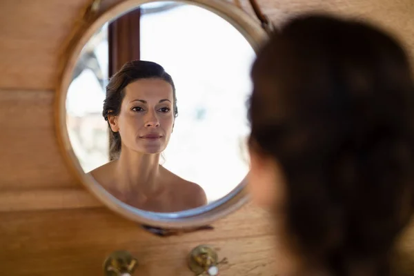 Женщина смотрит на зеркало в коттедже — стоковое фото