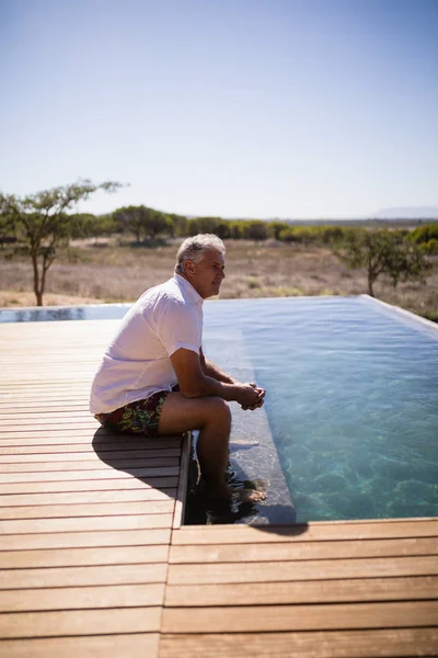 Homme réfléchi assis près de la piscine — Photo