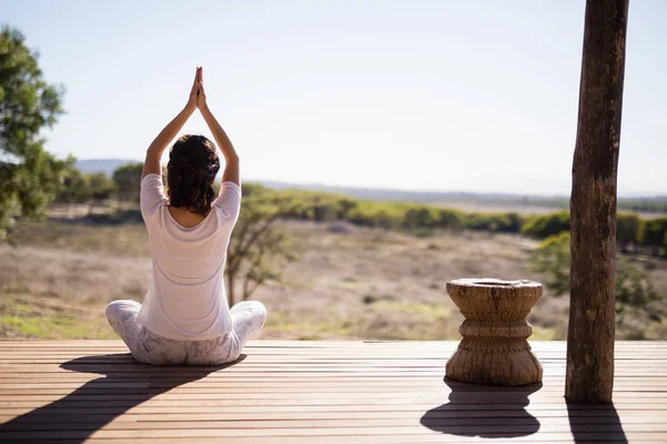 Frau praktiziert Yoga auf Holzplanke — Stockfoto