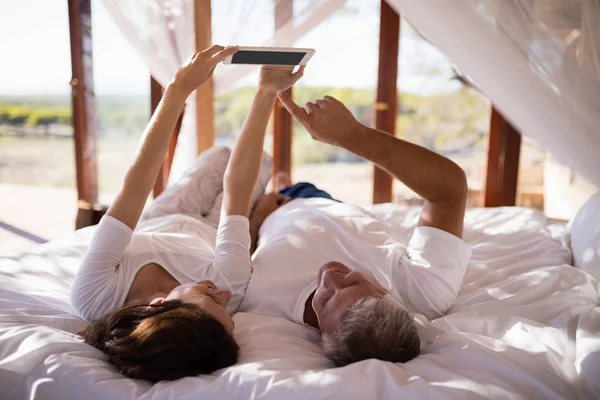 ベッドでタブレットを使用して幸せなカップル — ストック写真