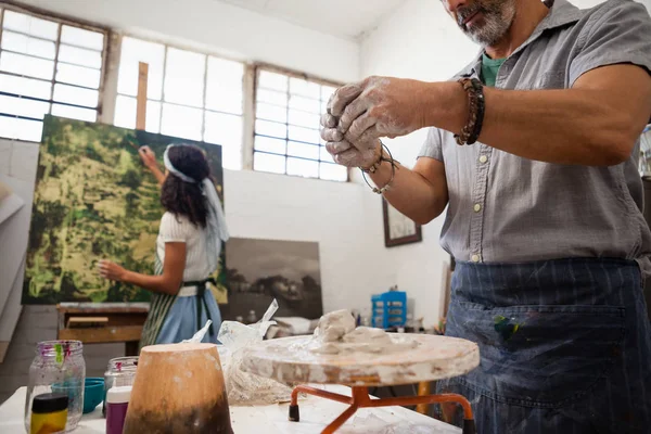 Hombre moldeando arcilla mientras mujer pintura sobre lienzo — Foto de Stock