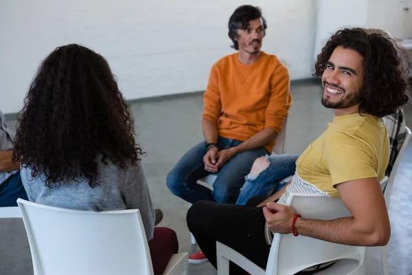 Porträtt av leende man sitter med vänner — Stockfoto