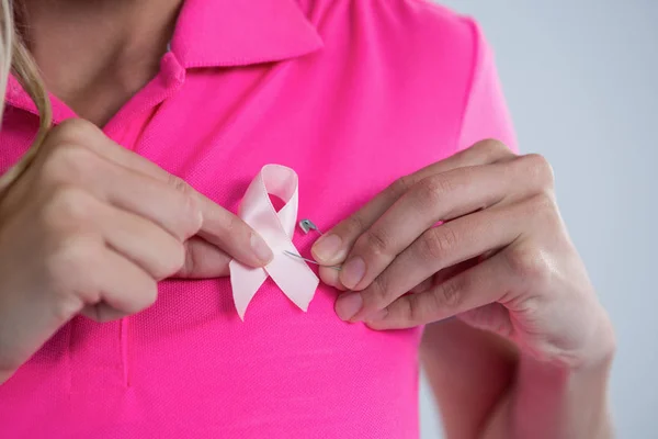Woman attaching pink ribbon — Stock Photo, Image