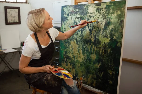 Mujer atenta pintura sobre lienzo — Foto de Stock