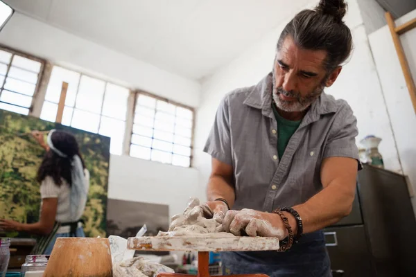 Uomo stampaggio argilla mentre la donna pittura su tela — Foto Stock