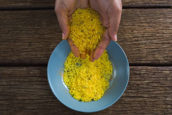 Manos vertiendo arroz en un tazón — Foto de Stock