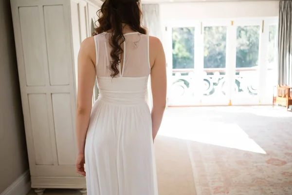 Noiva em vestido de casamento de pé em casa — Fotografia de Stock