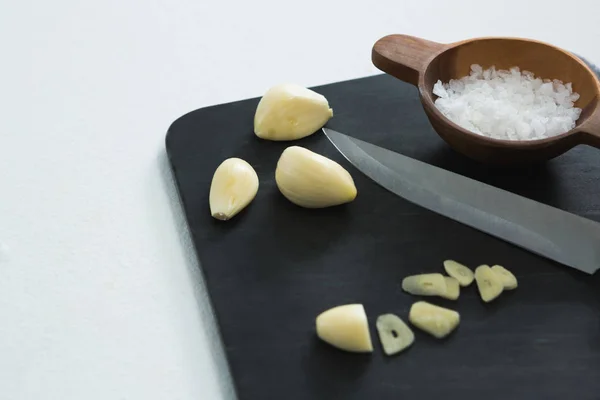Chopped garlic with bowl of sea salt and knife — Stock Photo, Image